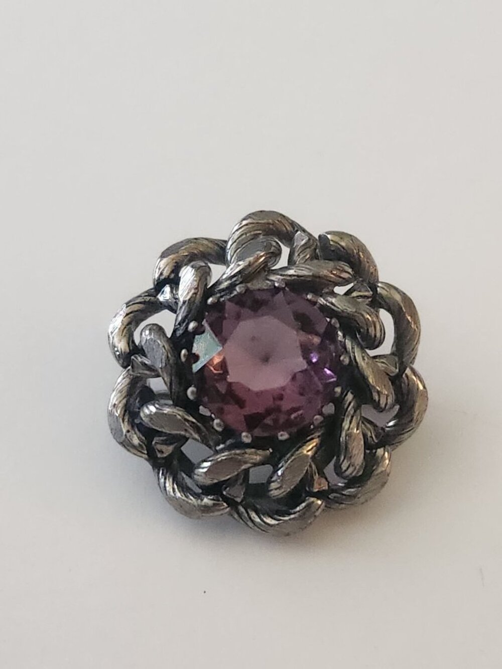 The image appears to show a vintage silver-tone brooch or button featuring a cen
